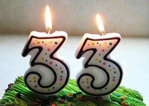 Зеленый торт со свечками в форме цифры 33 в честь праздника